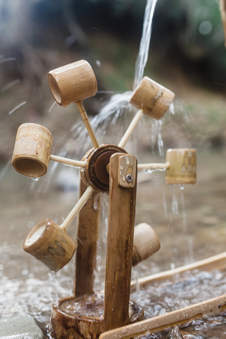 Wooden water wheel with bamboo buckets in a natural setting