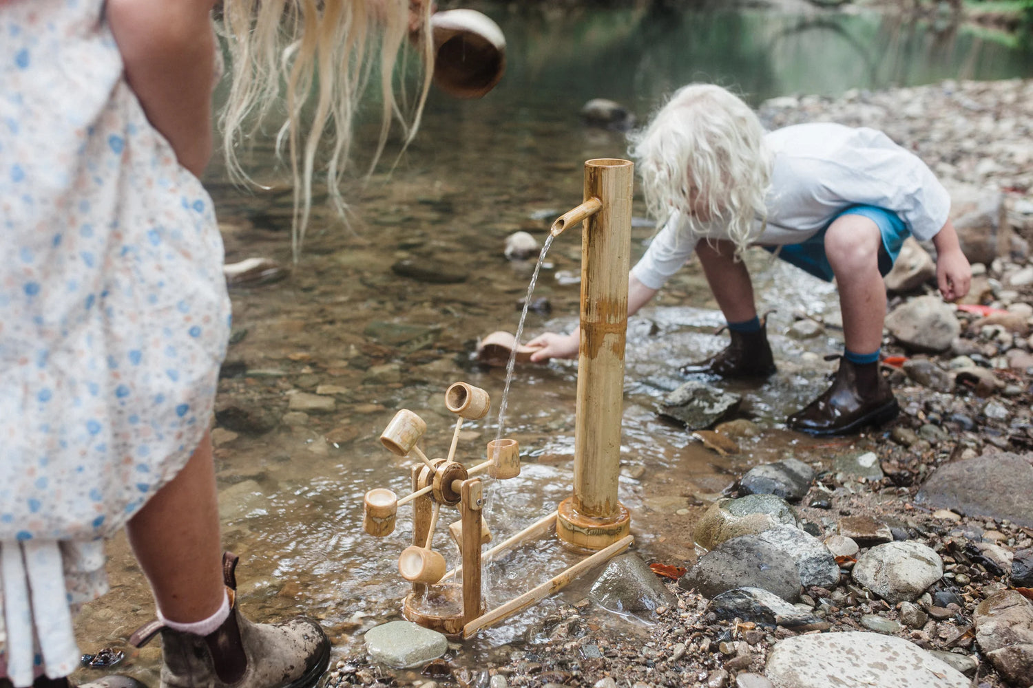 Children playing by a water pump in a natural setting